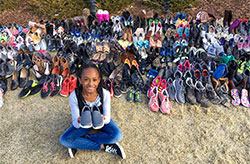 Girl sitting in front of many pairs of shoes