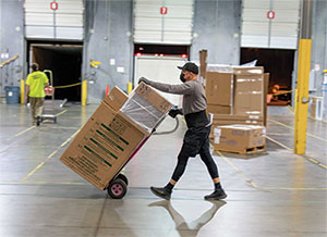 Person in warehouse moving box on dolly