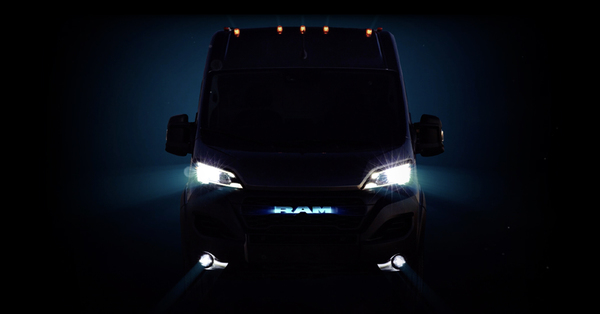 Truck at night with only headlights, outline of cab, and the word 'RAM' on the front visible